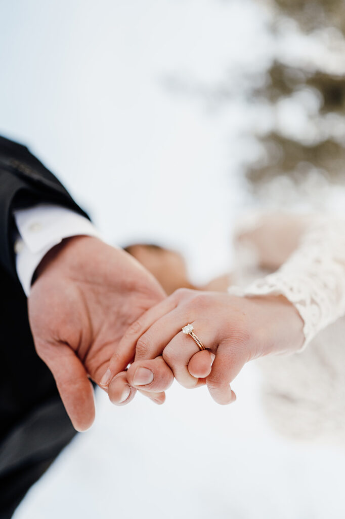 Bride and groom holding hands, wedding ring close up