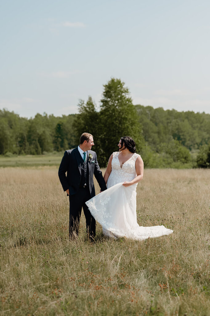 The bride and groom are captured enjoying each other's company, surrounded by the tranquil fields of the Ivy Black venue