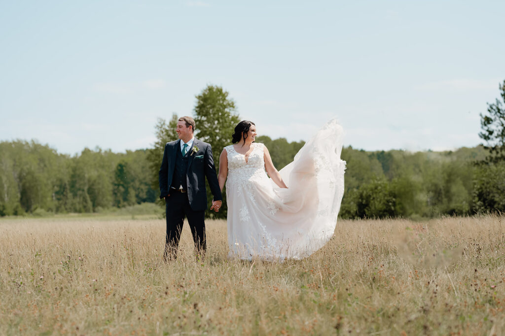 The bride and groom are caught in a quiet moment, surrounded by the tranquil fields of the Ivy Black venue