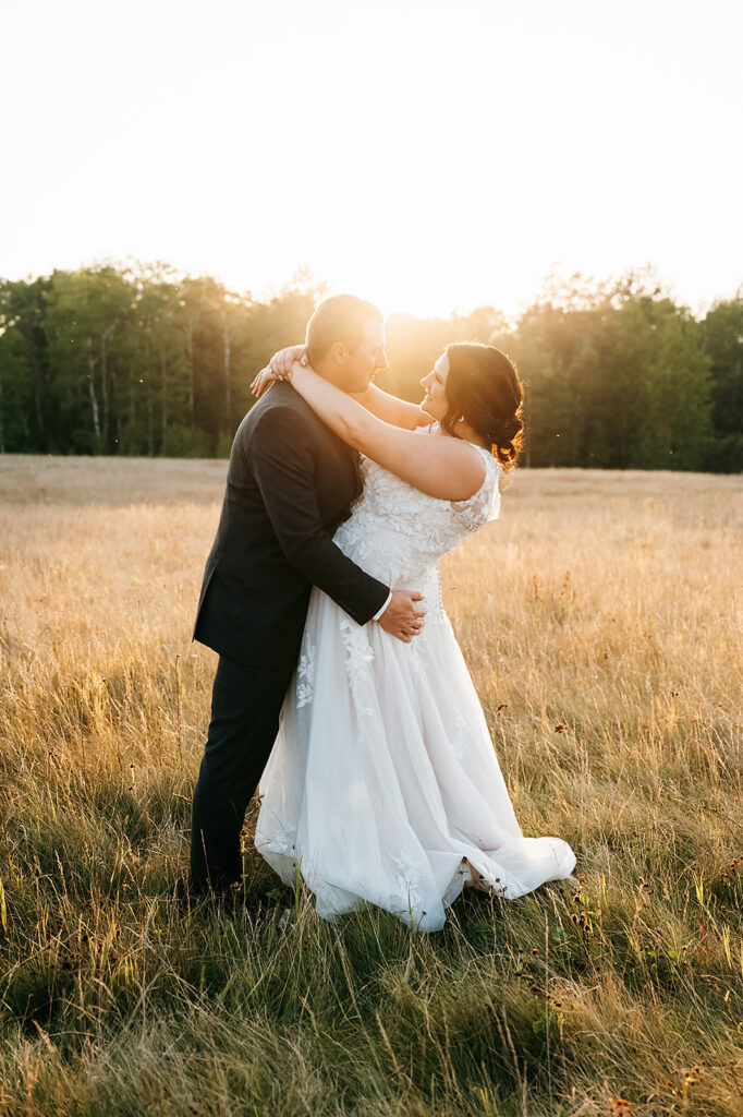 Golden hour casts a warm glow over the bride and groom, captured in a tender moment at the Ivy Black venue