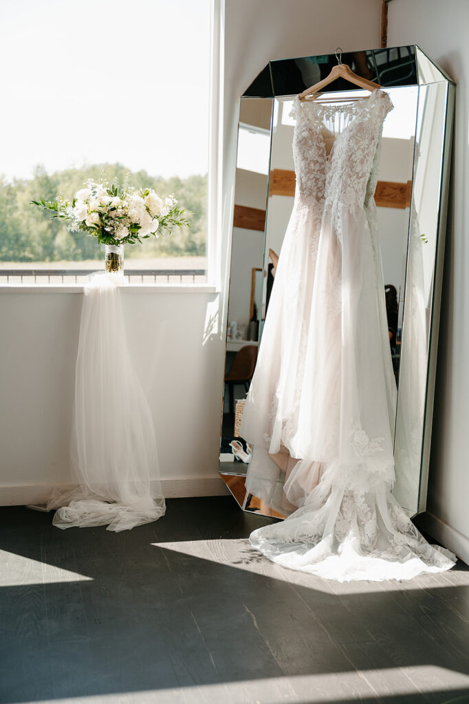 Bride's dress hanging on the mirror by the window