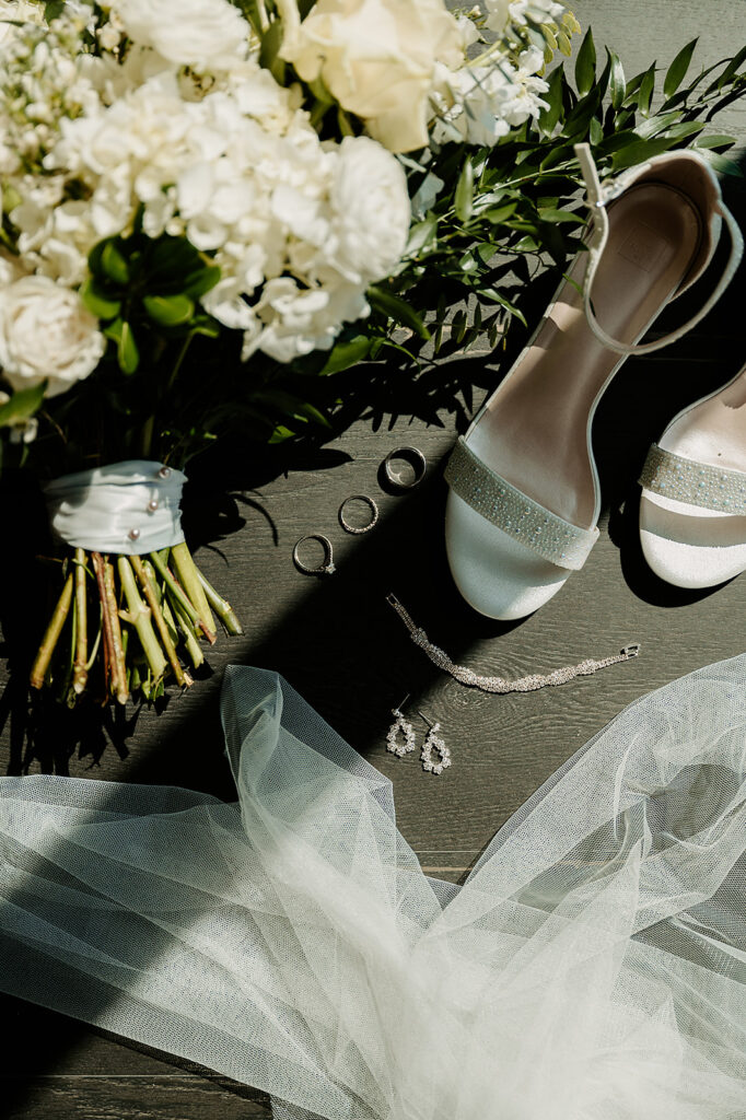 Elegant wedding detail flatlay on dark hardwood floors