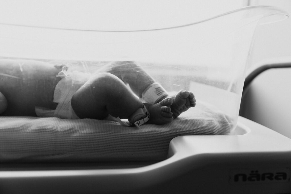 Close-up of a sleeping infant's tiny hands and feet, photographed in the first 48 hours after birth, with a focus on the details of newness.