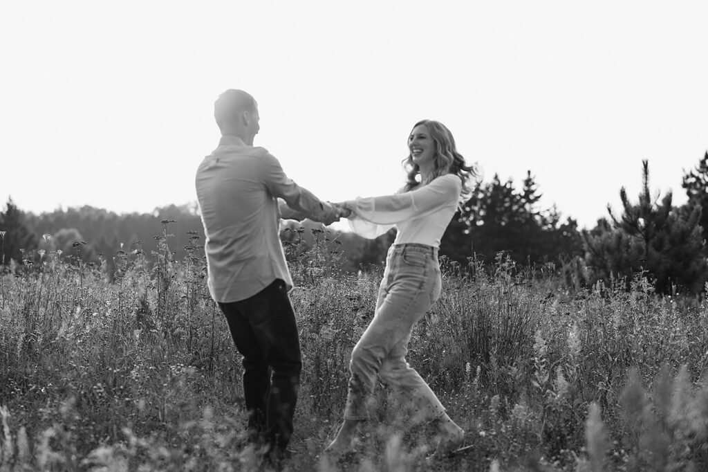Future bride and groom playing around with each other in a scenic field in Bemidji