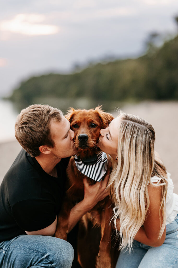 Engaged couple and their cute brown dog captured in a romantic setting by the water in Bemidji