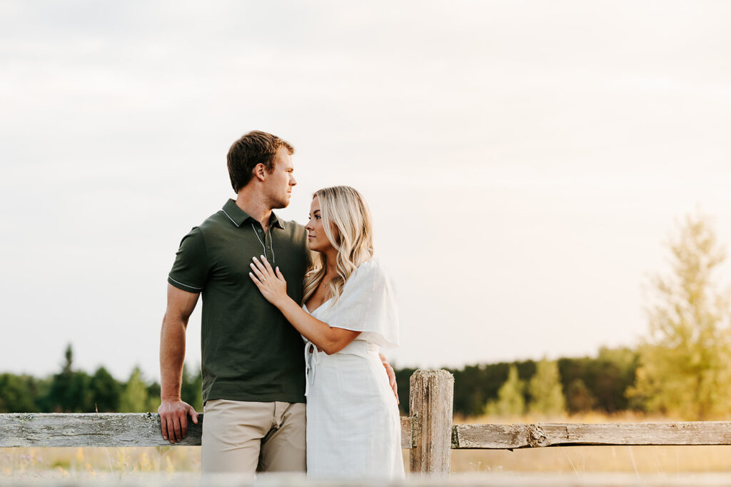 Happy couple posing in a sunlit field in Bemidji during their engagement photo session