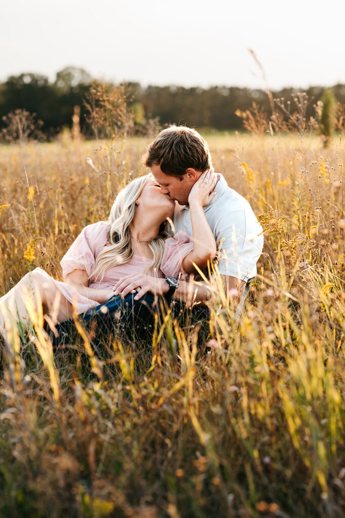 Couple sitting together amidst tall grasses for field engagement photos in Bemidji, MN