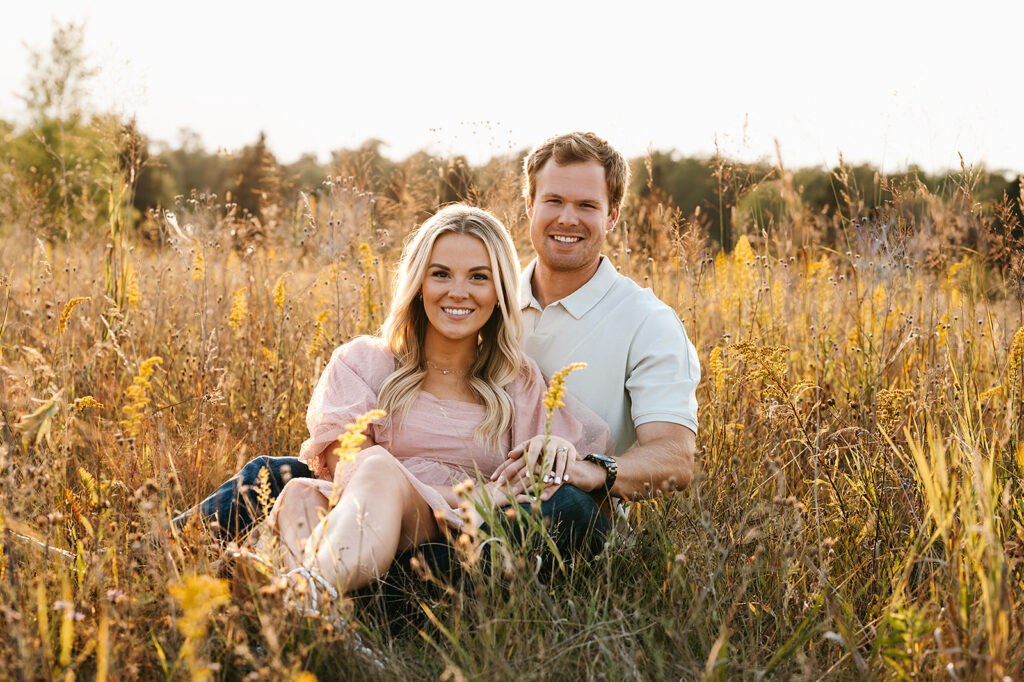 Couple sitting together amidst tall grasses for field engagement photos in Bemidji, MN