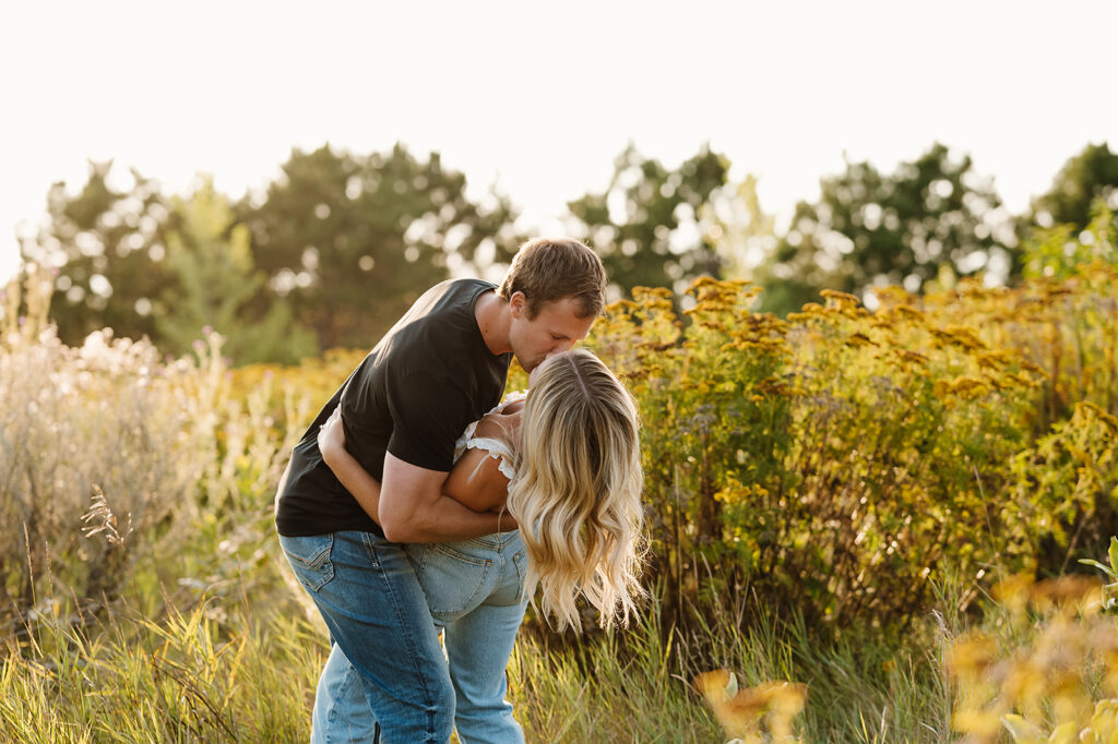 Engaged couple captured in a romantic setting among wildflowers in Bemidji
