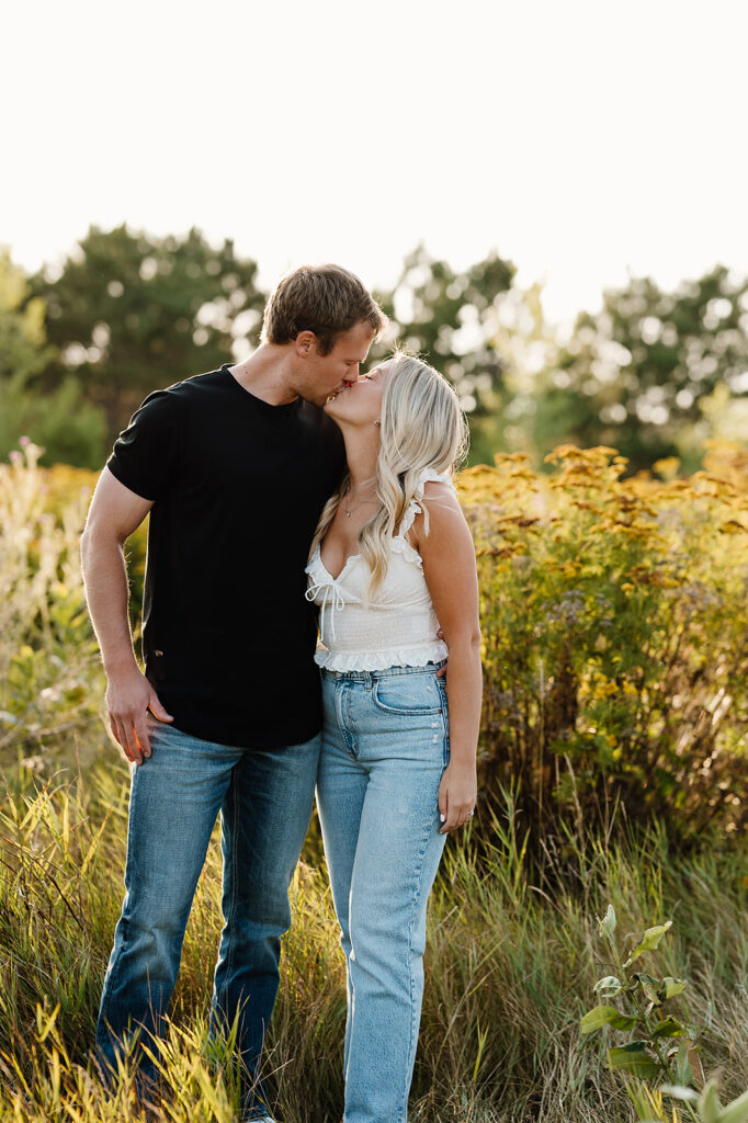 Field engagement photos showcasing a loving couple embracing among golden grasses