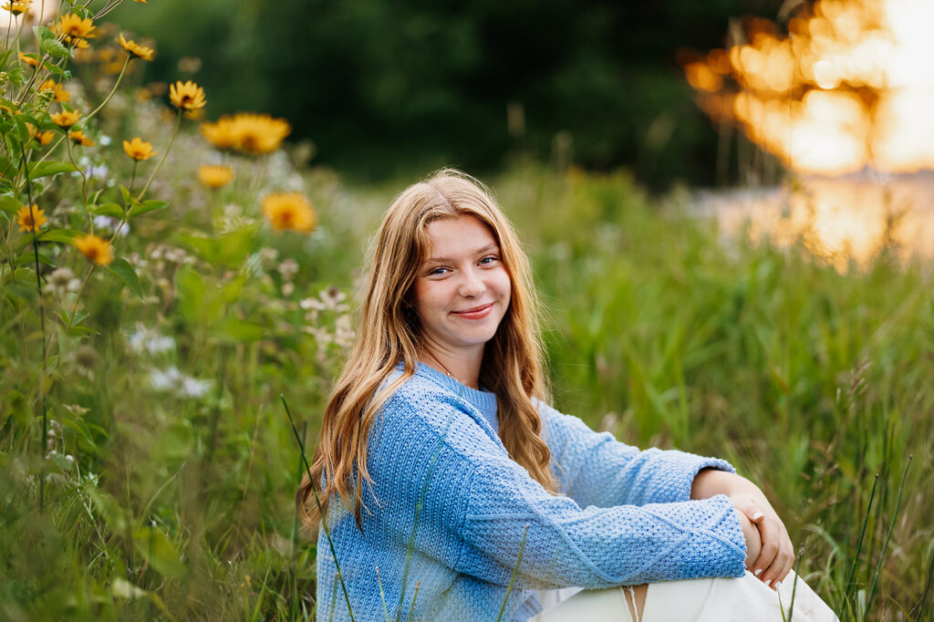 A girl student smiling at Lake Bemidji State Park, surrounded by lush greenery, exemplifying the natural beauty of Minnesota in her senior photo