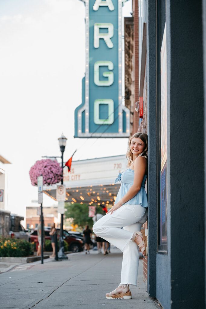 A girl posing for her senior photos, with downtown Fargo in the backdrop