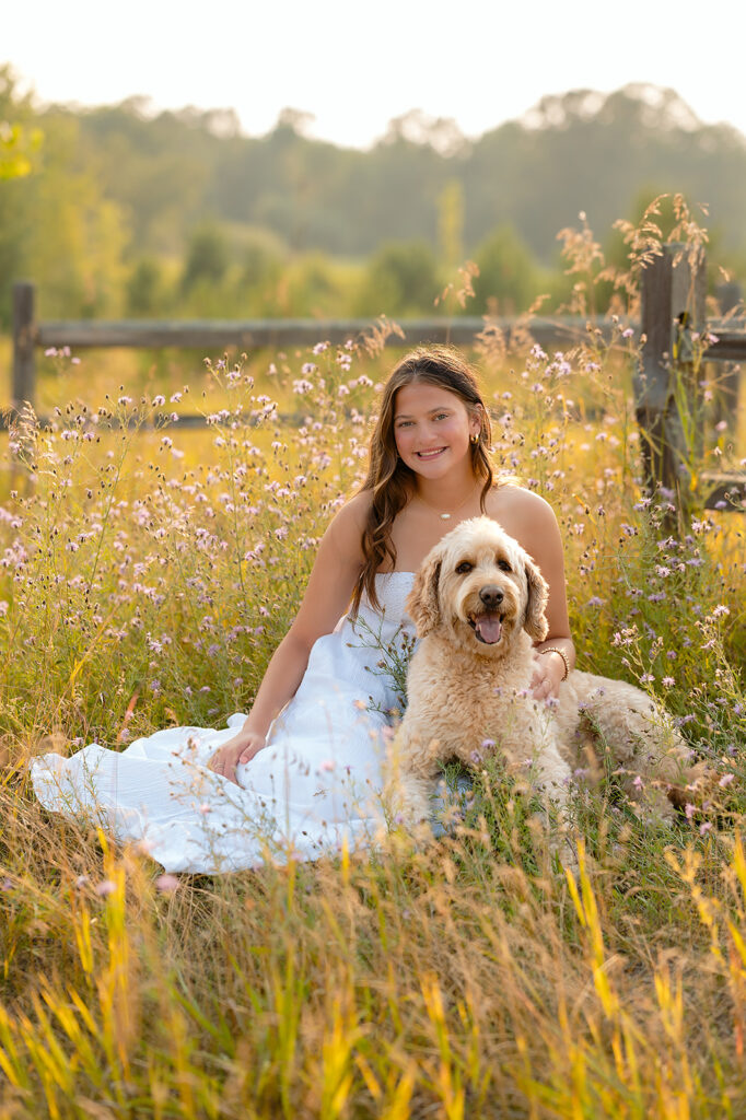 Senior photos in Minnesota featuring a girl sitting in a lush field with her doggo