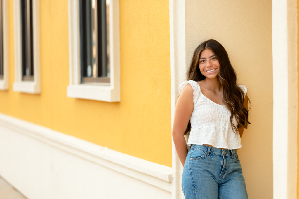 smiley girl posing next to a colorful wall for her senior session in minnesota