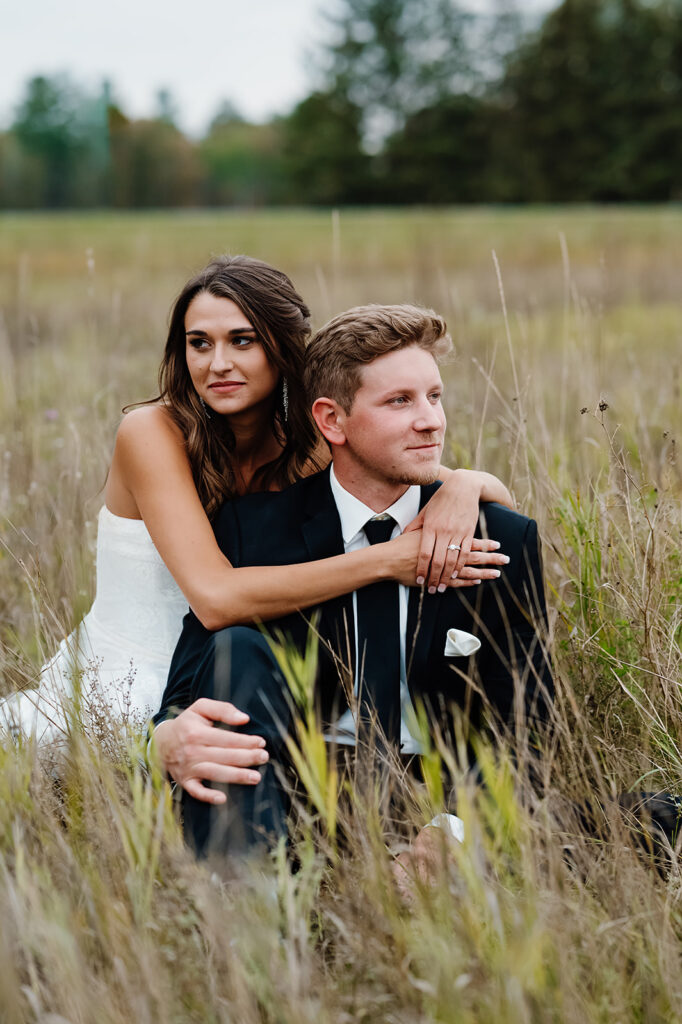bride and groom sitting together in a beautiful field