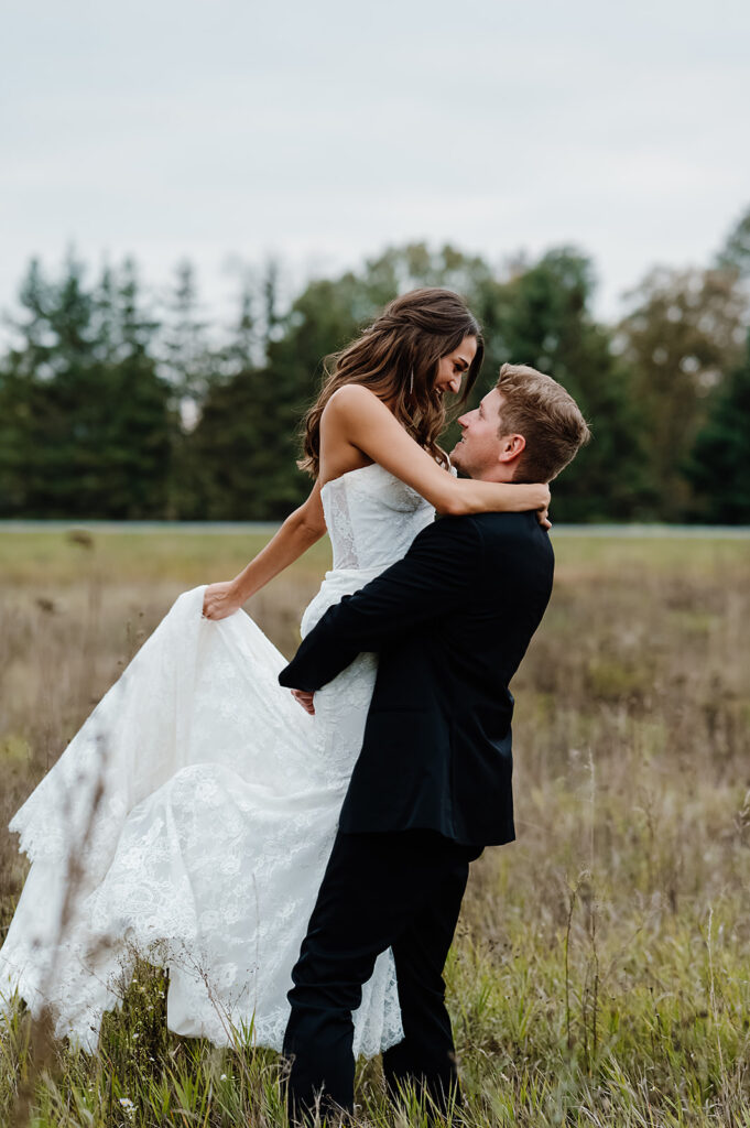 romantic and plaful bride and groom wedding portraits in a gorgeous, lush field