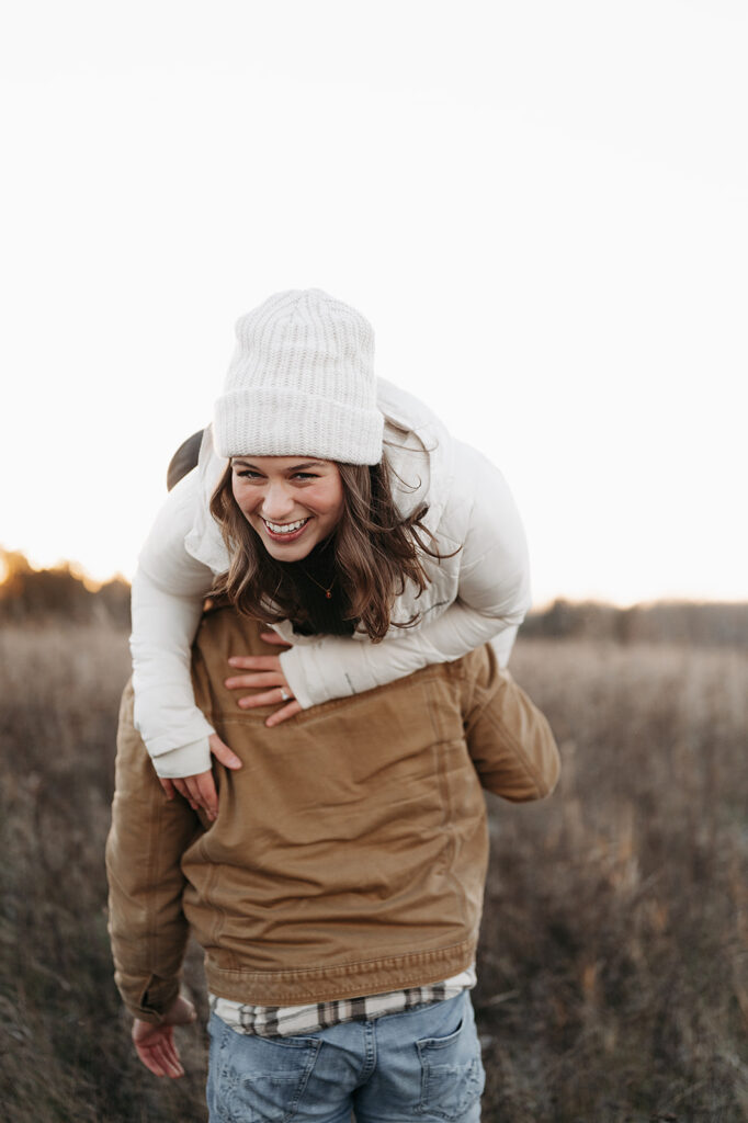 playful winter engagement photos where Cole has thrown Alexis over his shoulder