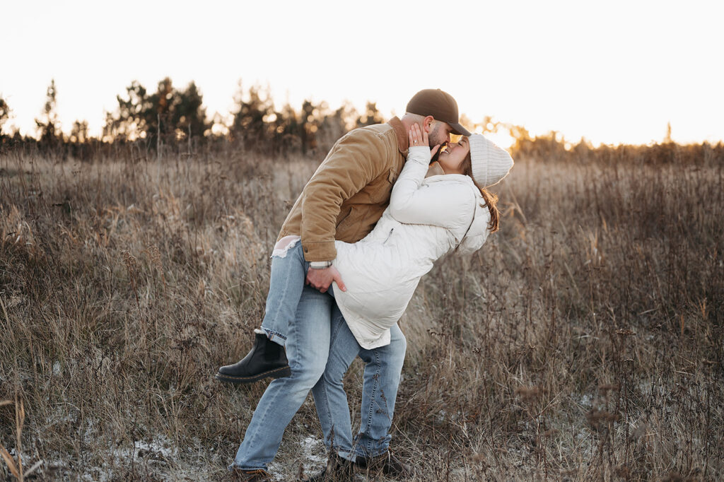 romantic and playful winter golden hour engagement photos in a gorgeous field in Minnesota, couple cute wearing winter coats and jeans