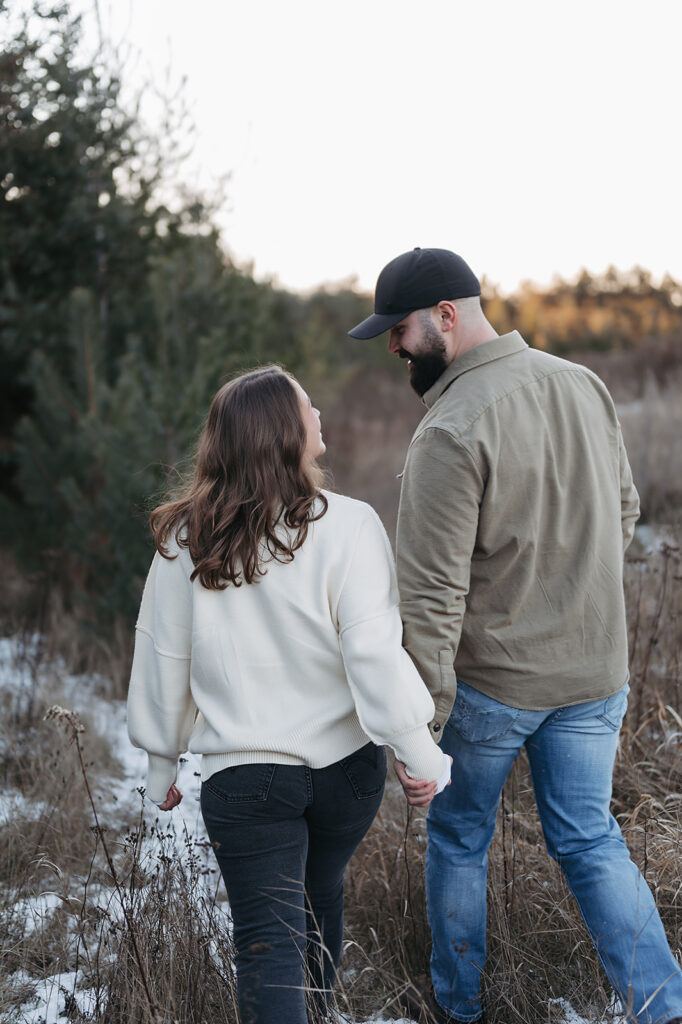Alexis and Cole roaming a snow covered field together for their engagement session in Bemidji, MN