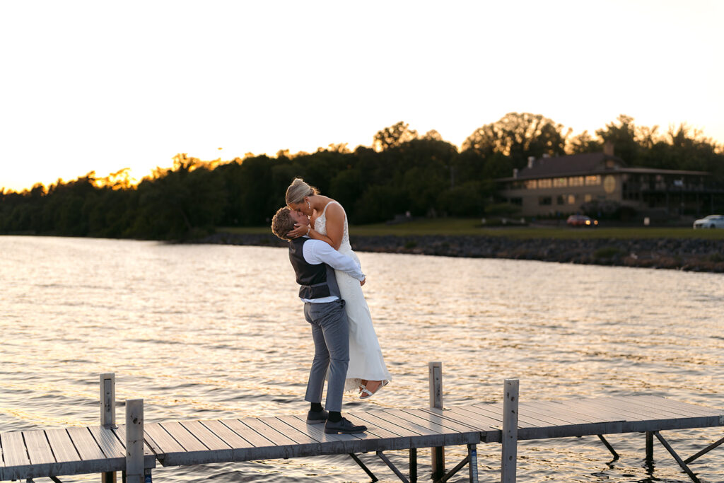 bride and groom kissing on the docks at bemidji country club