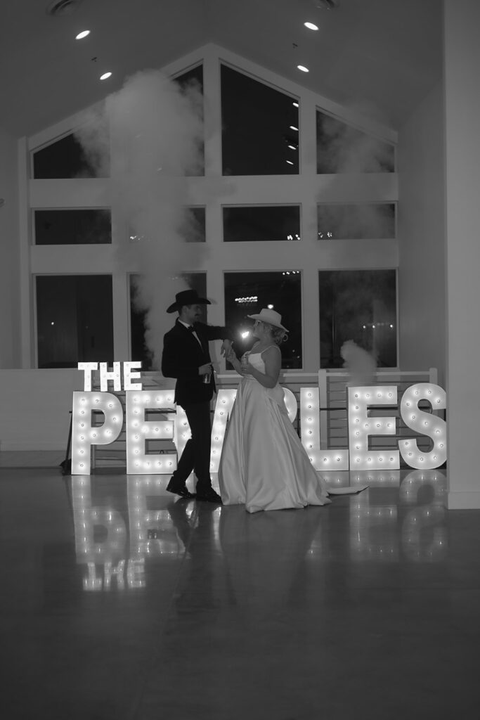 bride and groom first dance in front of their bright marquee letters spelling “The Pemble’s”