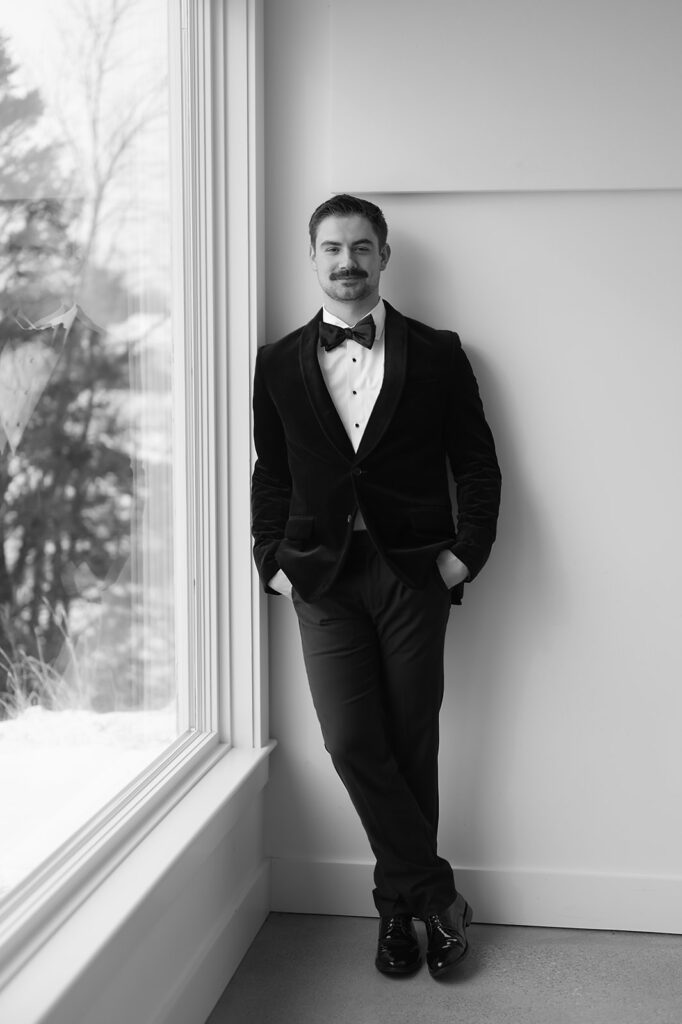 groom portrait in front of the large windows at The Aisling during winter wedding