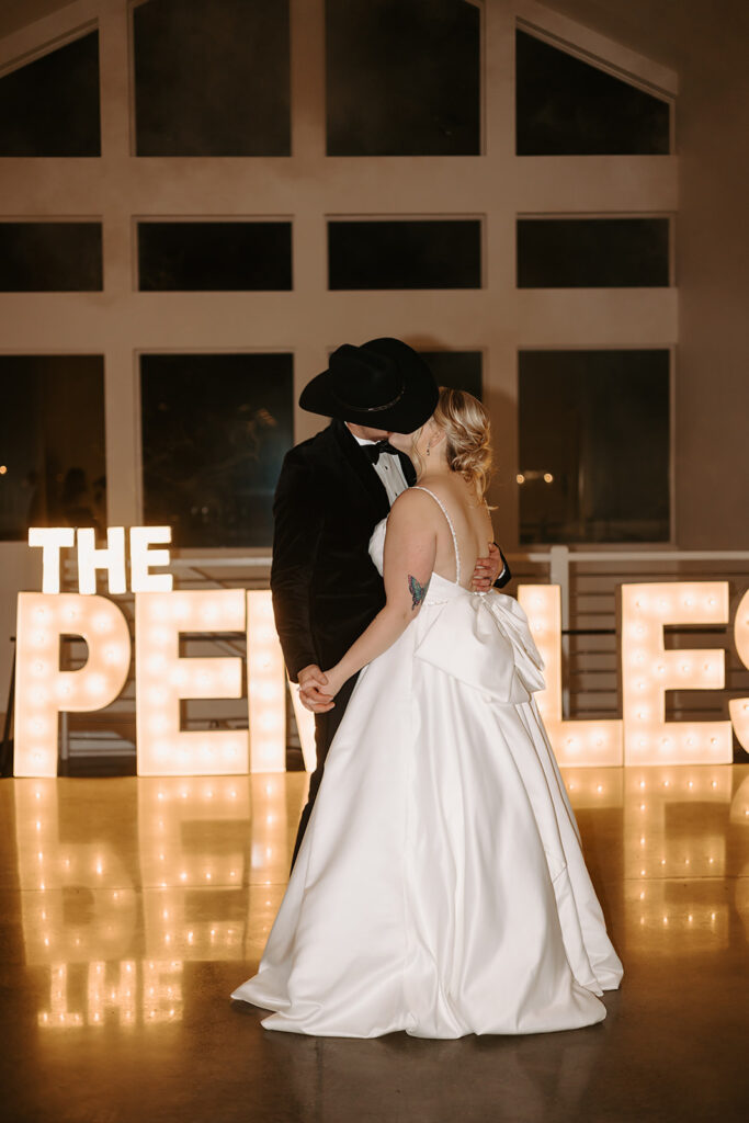 bride and groom first dance in front of their bright marquee letters spelling “The Pemble’s”