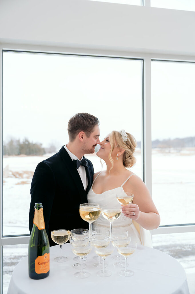 bride and groom drinking champagne next to their champagne tower