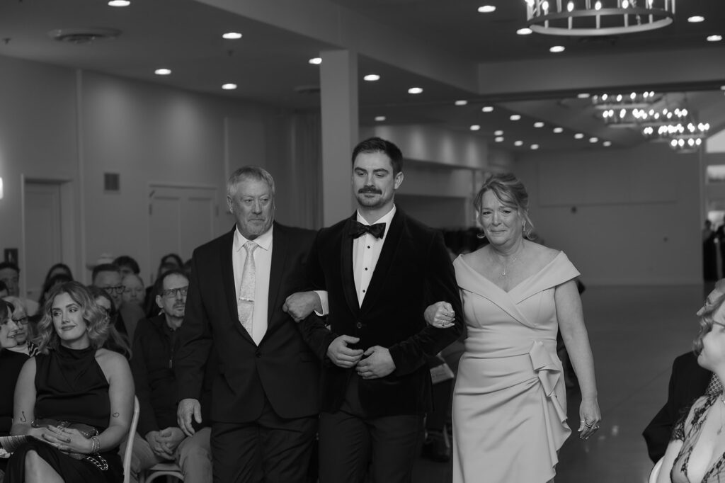 groom walking down the aisle with parents