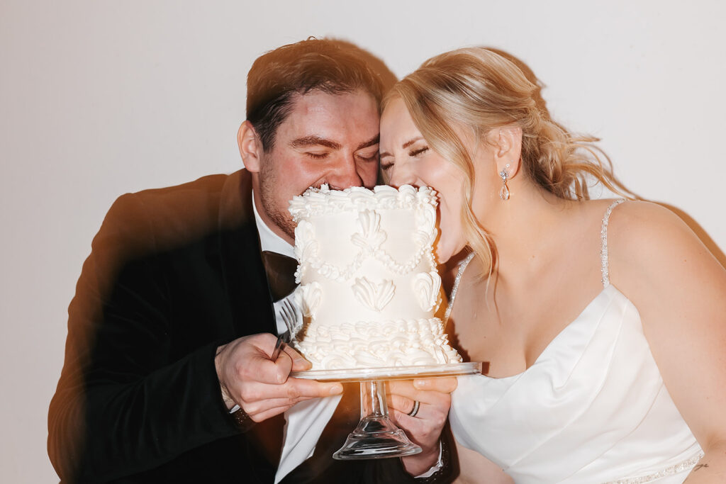 Bride and groom sitting on the floor eating cake together late at night at The Aisling