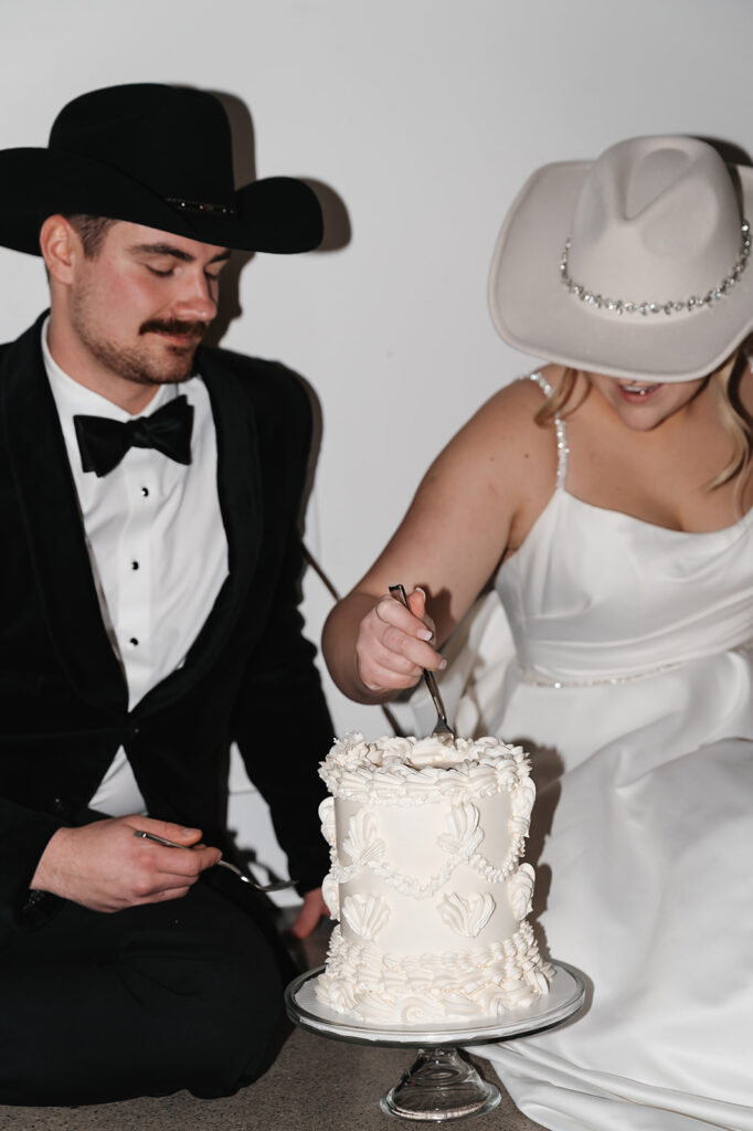 Bride and groom sitting on the floor eating cake together late at night at The Aisling