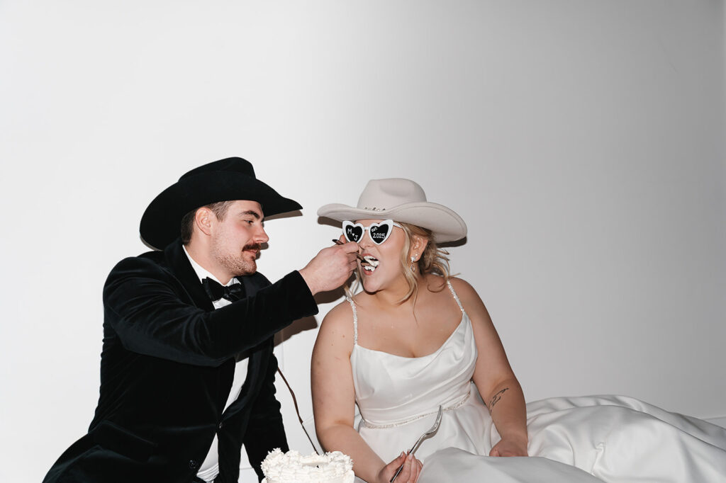 Bride and groom sitting on the floor eating cake together late at night at The Aisling