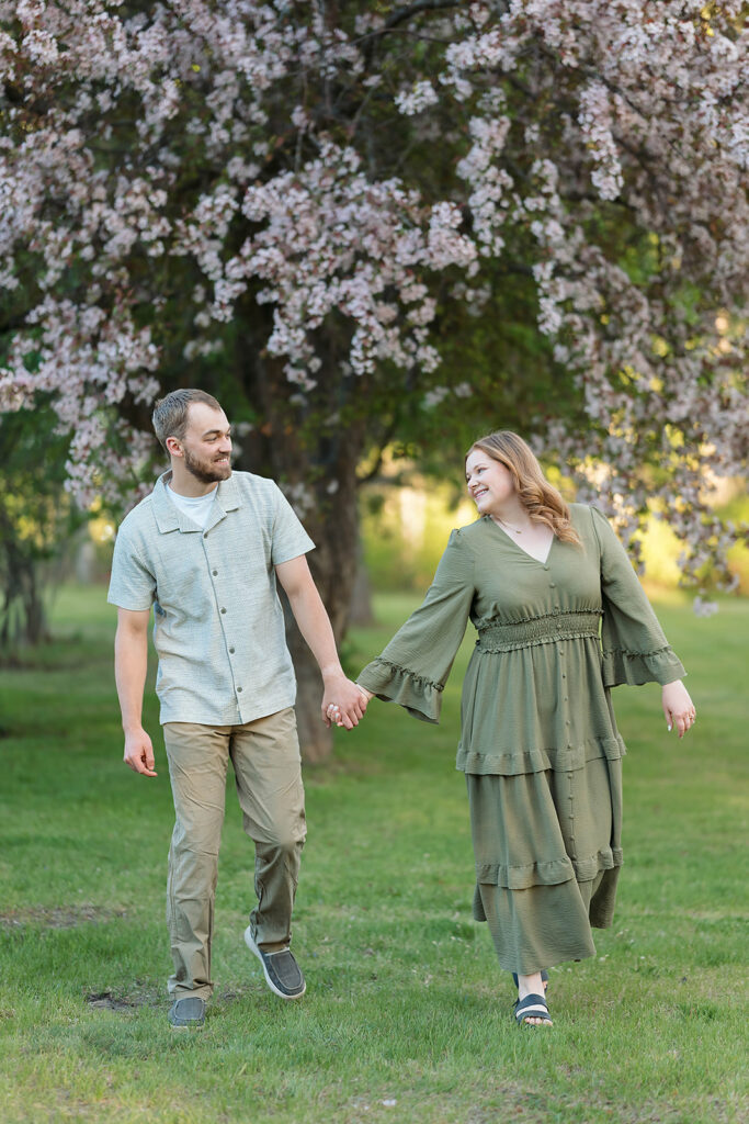 couple walking holding hands with blooming crab trees in the backdrop