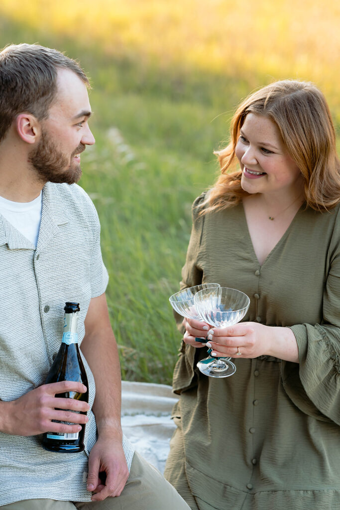 couple drinking champagne in a field during golden hour