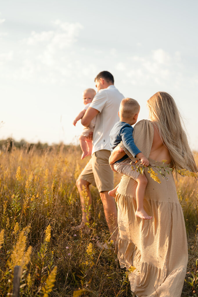mom, dad and their two little sons in a  lush golden field in Minnesota