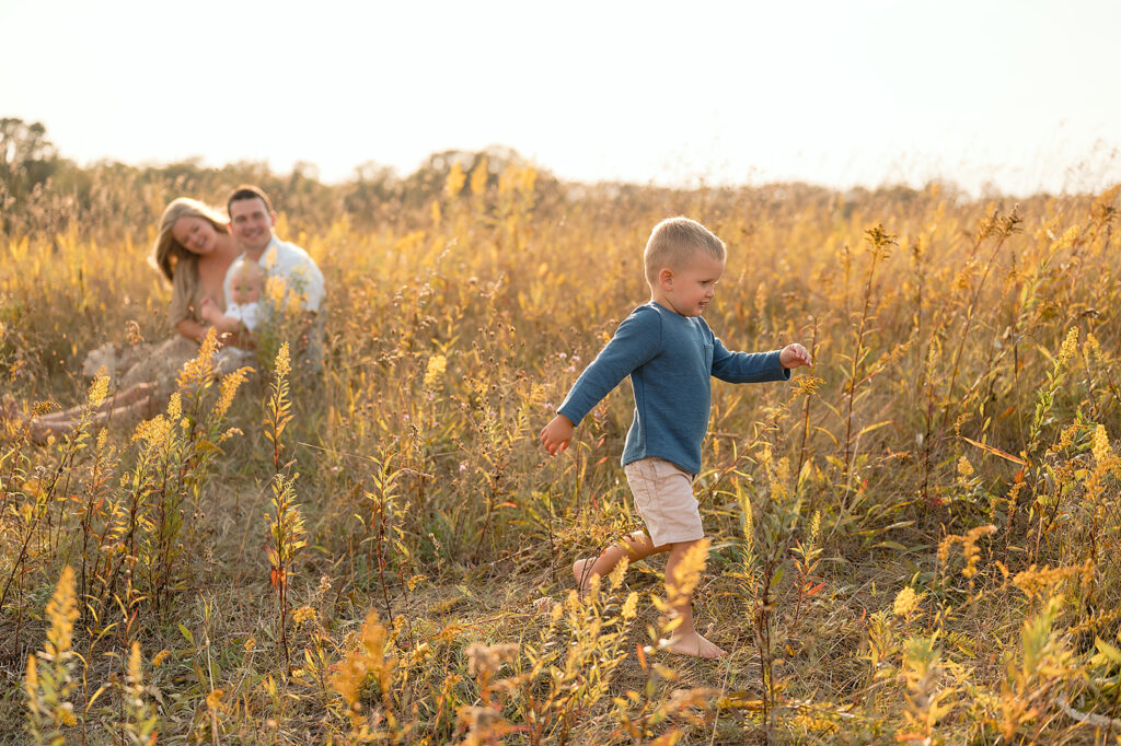 mom, dad and their two little sons in a  lush golden field in Minnesota