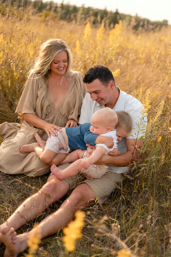 mom, dad and their two little sons in a  lush golden field in Minnesota