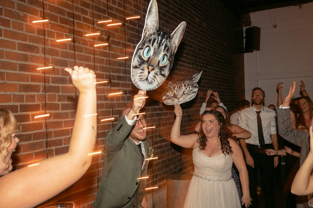 bride and groom carrying around fatheads of their cats during the reception at the neu neu wedding venue 