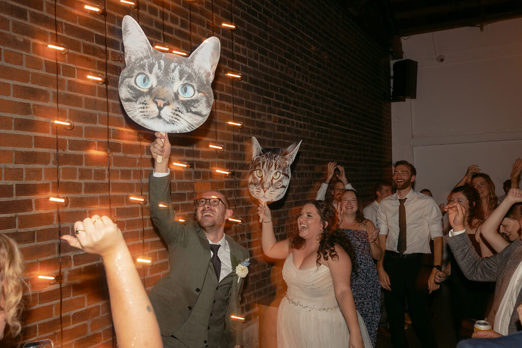 bride and groom carrying around fatheads of their cats during the reception at the neu neu wedding venue 