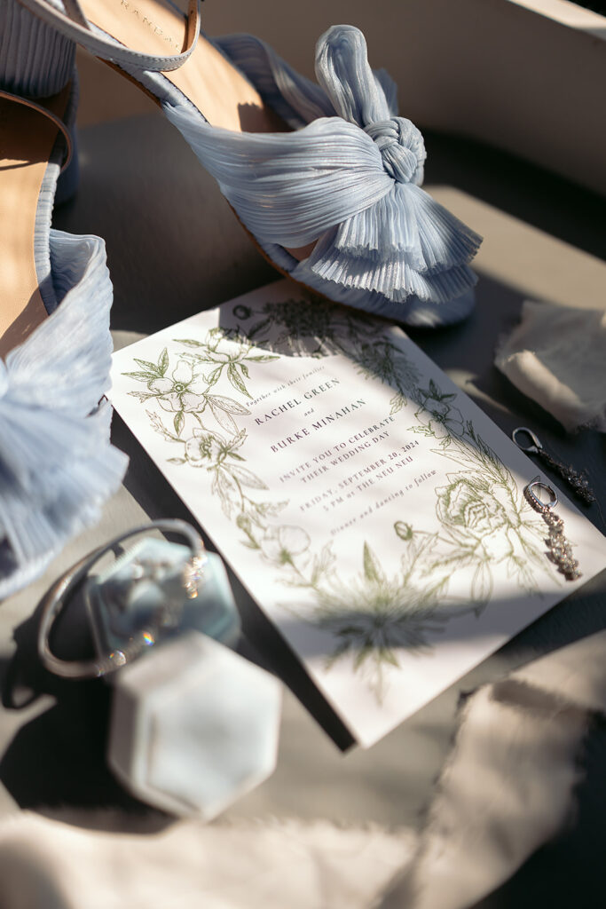 elegant blue wedding detail flatlay of rings, shoes and invitation suite
