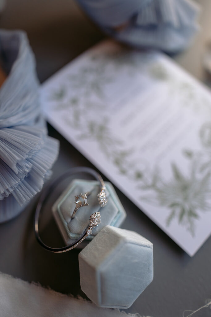 elegant blue wedding detail flatlay of rings, shoes and invitation suite