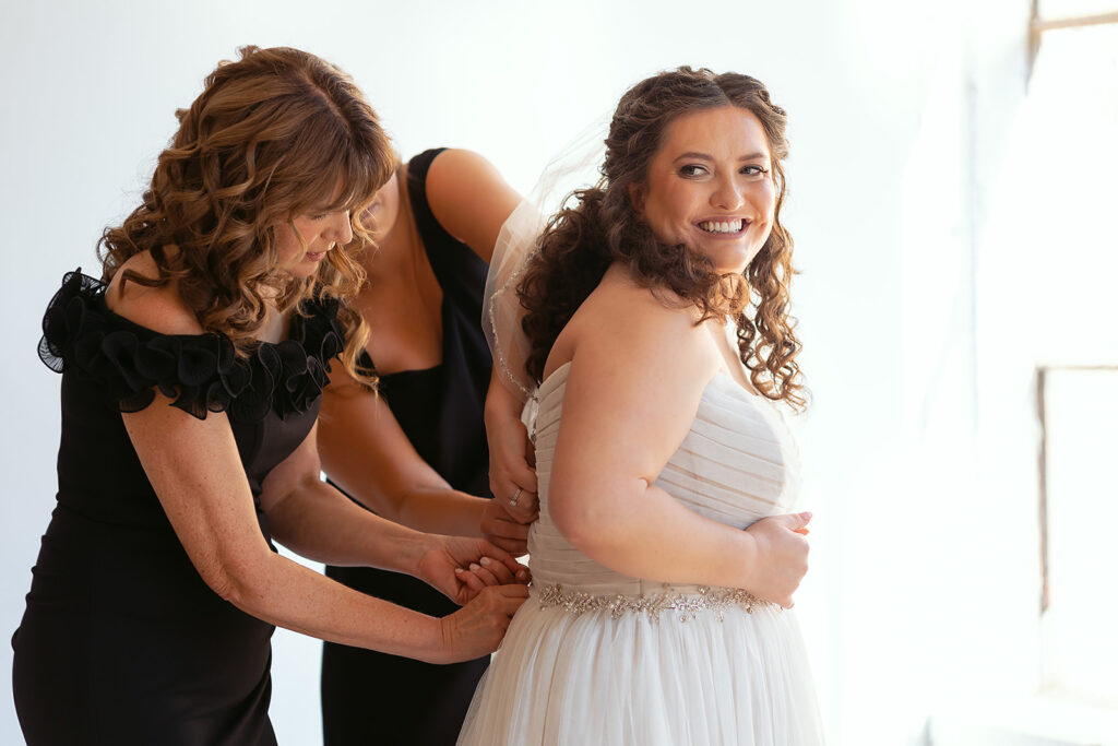 mom helping bride get into the wedding dress
