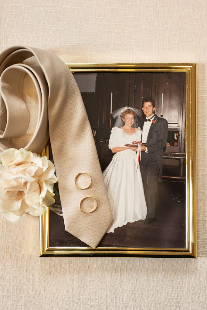 wedding details of a tie, rings, and groom's parent photos