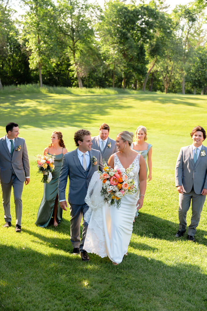 bride and groom and their wedding party on the golf course during the bemidji country club wedding day