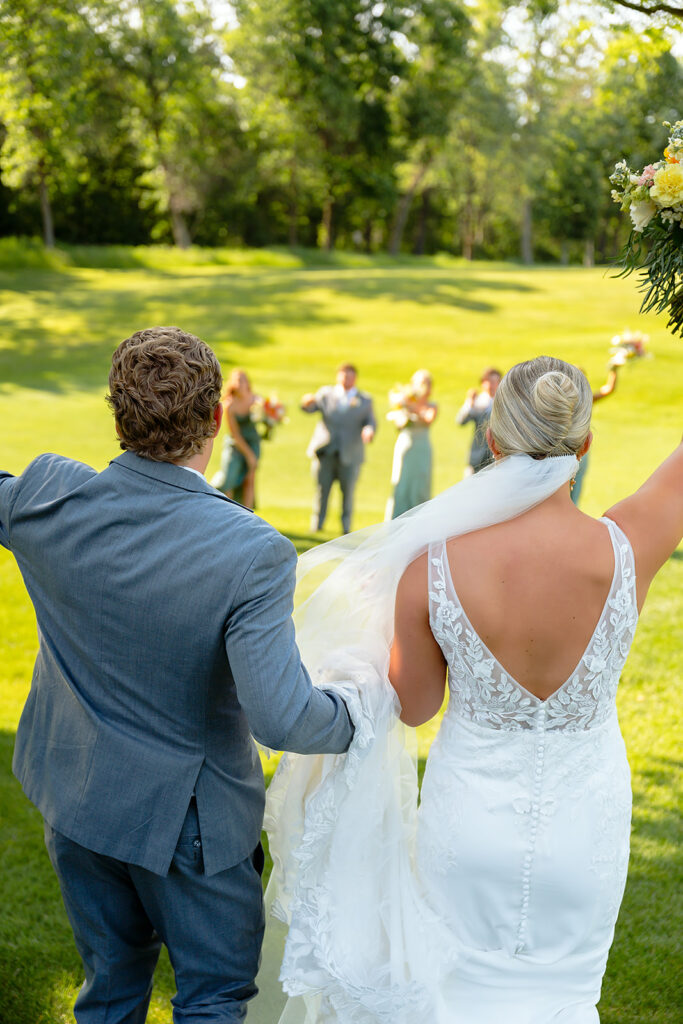 bride and groom and their wedding party on the golf course during the bemidji country club wedding day