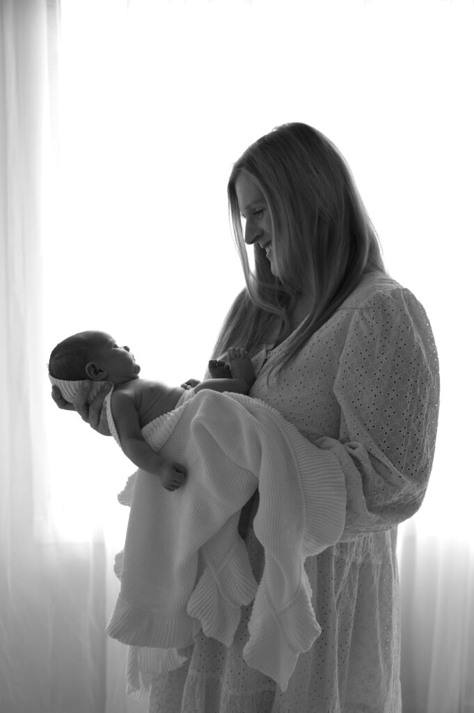 mom and newborn next to a window at the sunroom studio in bemidji mn