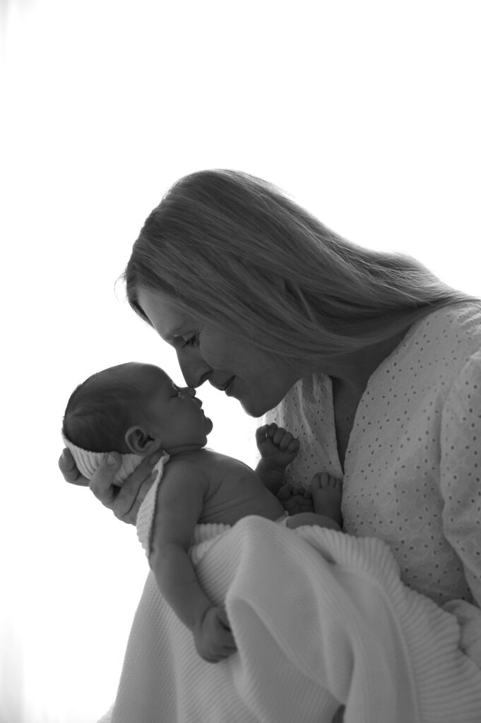 mom and newborn next to a window at the sunroom studio in bemidji mn
