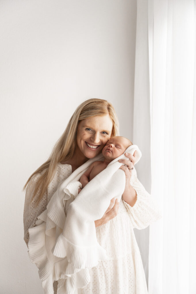 mom and newborn next to a window at the sunroom studio in bemidji mn