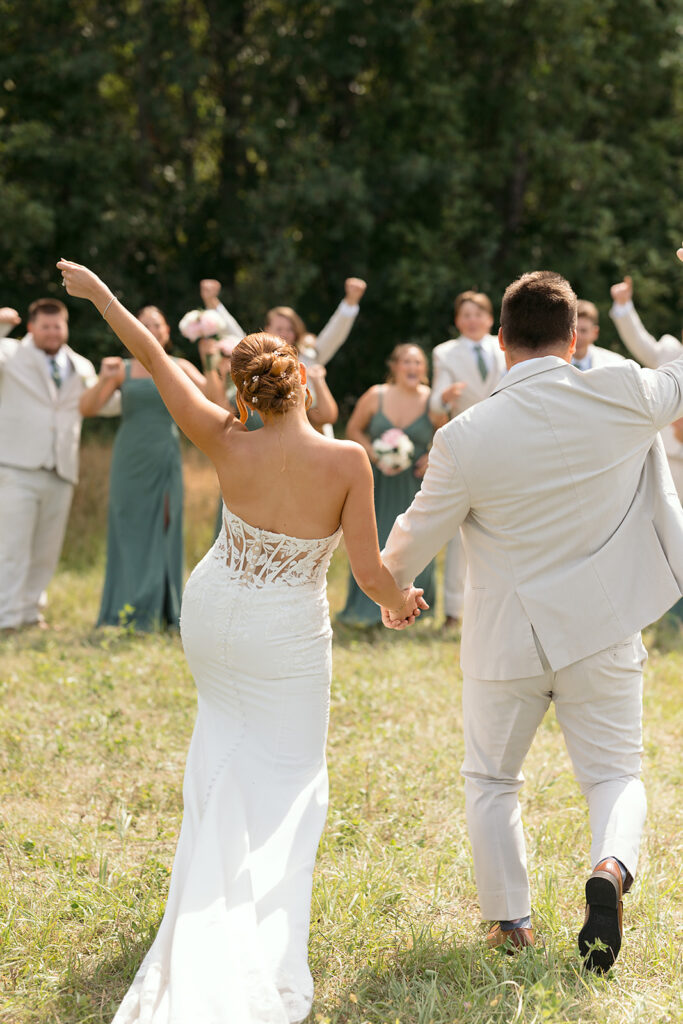 bride and groom surrounded by cheering wedding party