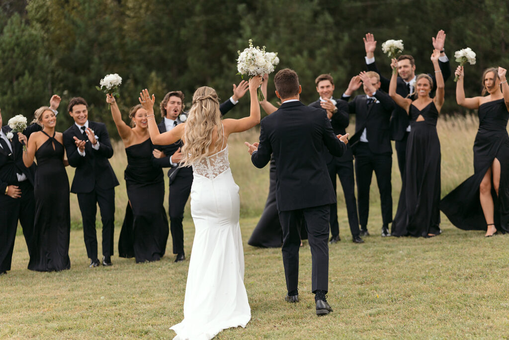 wedding couple walking towards their cheering wedding party